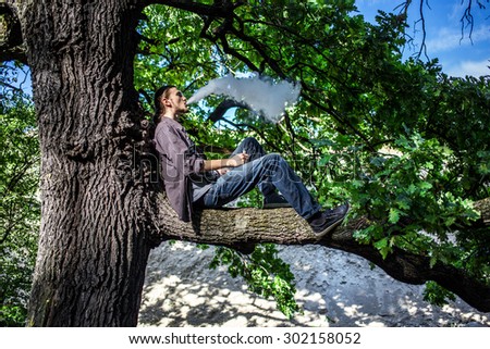 stock-photo-young-man-vaping-electronic-cigarette-and-sitting-on-the-tree-daylight-summer-shot-302158052.jpg