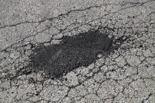 87793561-cracked-asphalt-road-surface-and-repair-patch.jpg