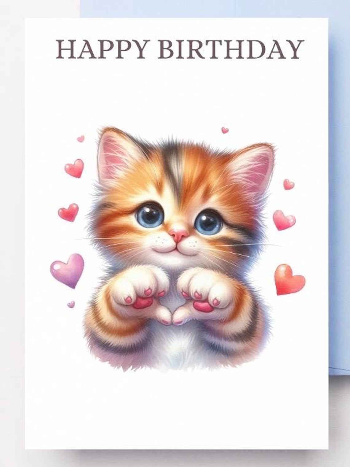 May include: A birthday card with the text 'HAPPY BIRTHDAY' at the top. A cartoon orange and white cat with blue eyes is holding its paws in a heart shape. There are pink hearts scattered around the cat.