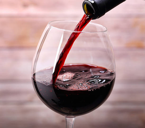 pouring-red-wine-into-glass-picture-id486071367
