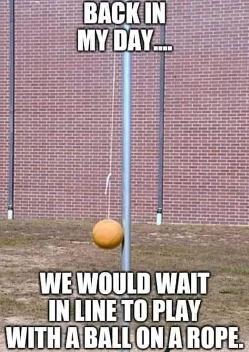 This may contain: an orange ball sitting on top of a pole in front of a brick wall with the caption back in my day we would wait in line to play with a ball on a rope